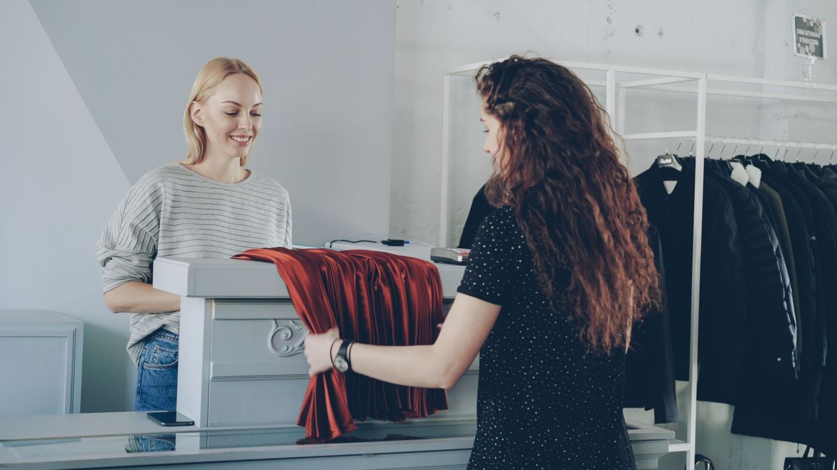 Продавец обслуживает покупательницу в небольшом магазине одежды